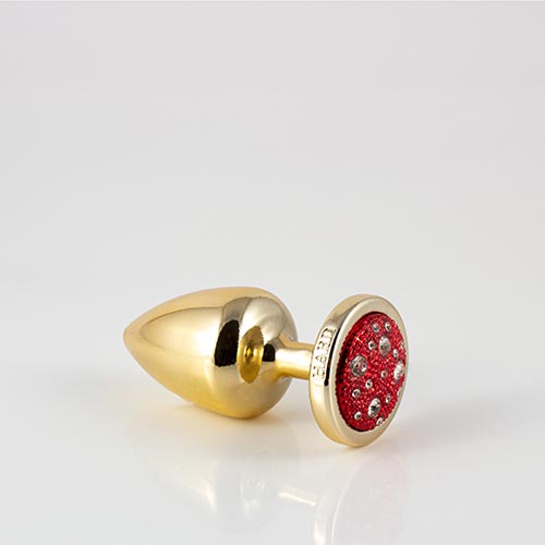 Plug LESS M (ABS) Dourado com Pedra Cravejada Vermelha